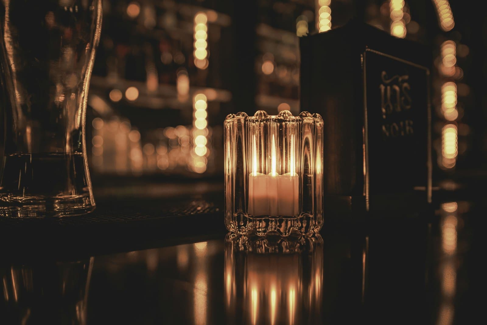 昏暗吧台上的一盞燭光與玻璃杯